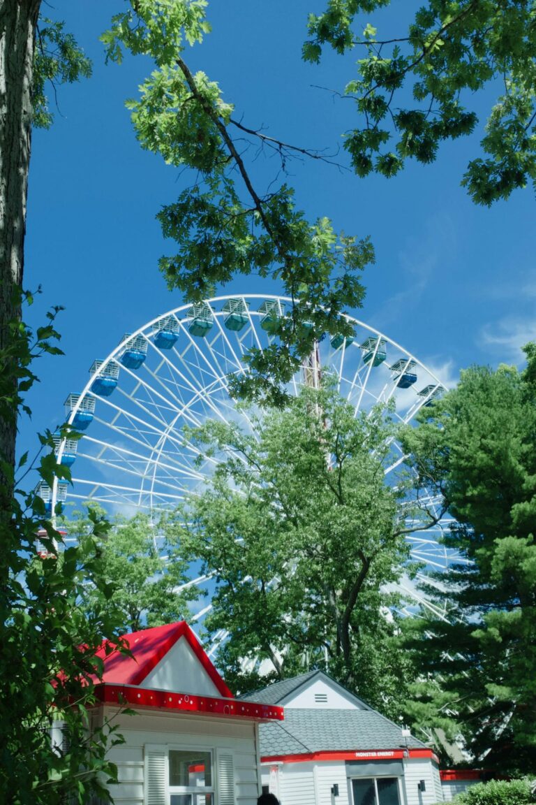A vibrant summer scene featuring a Ferris wheel peeking through lush greenery and a cozy house.